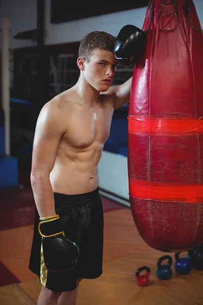 Tired boxer leaning on punching bag — Stock Photo, Image