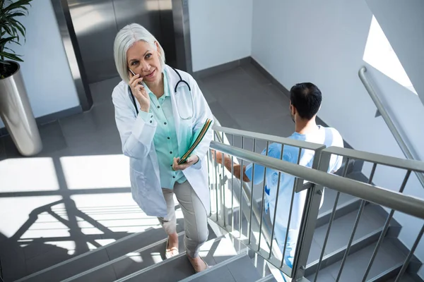 Doctor talking on phone on staircase — Stock Photo, Image