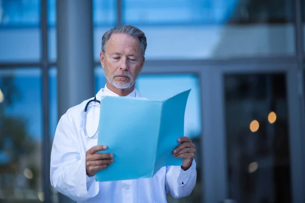 Cirujano masculino leyendo informe médico — Foto de Stock