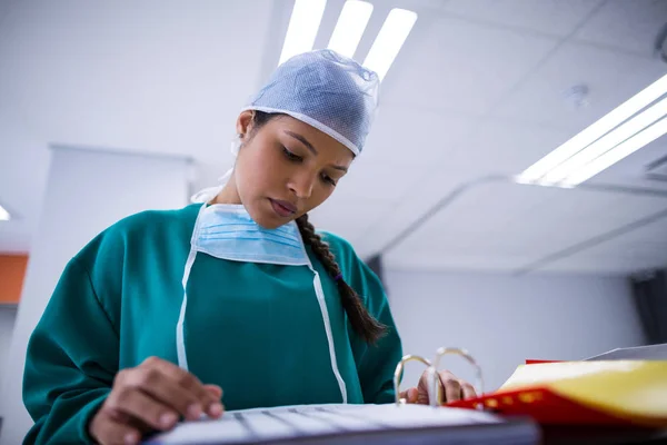 Cirurgiã lê relatórios em sala de operações — Fotografia de Stock