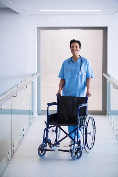 Portrait of female nurse standing with wheelchair — Stock Photo, Image