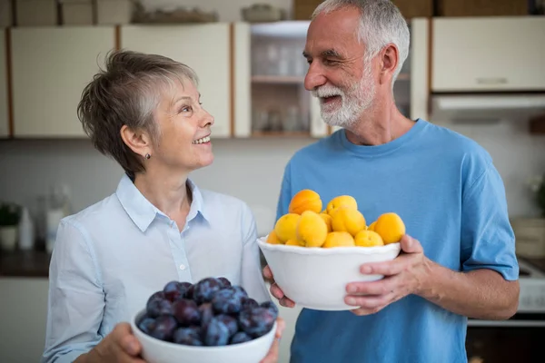 Starszy para gospodarstwa bowl morelowy i winogron — Zdjęcie stockowe