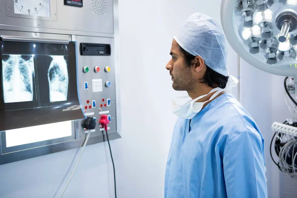 Male surgeon reading x-ray in operation theater — Stock Photo, Image