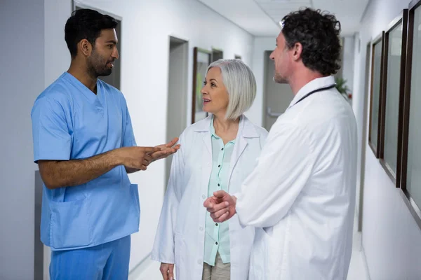 Doctors and surgeon interacting in corridor — Stock Photo, Image