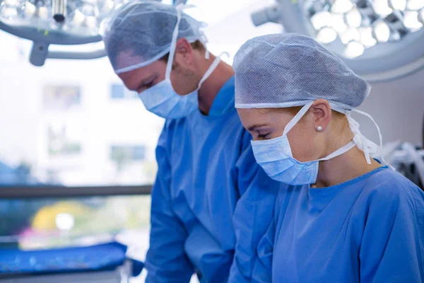 Mannelijke en vrouwelijke chirurg dragen chirurgisch masker — Stockfoto