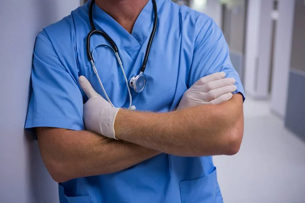 Surgeon standing with arms crossed in corridor — Stock Photo, Image