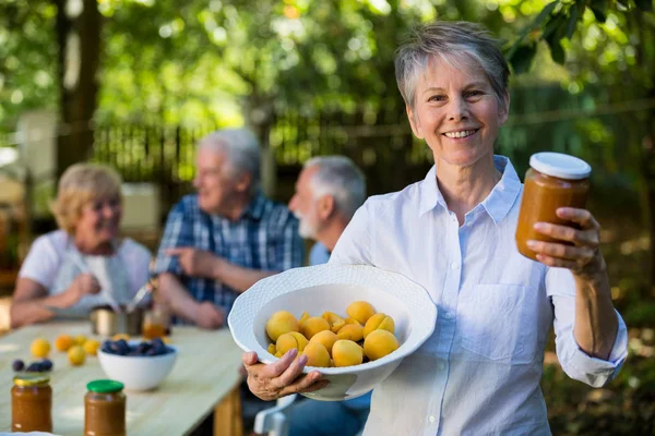 Senior vrouw met fles jam in tuin — Stockfoto