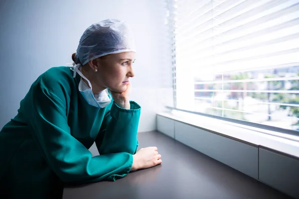 Przemyślane kobieta chirurg, patrząc przez okno — Zdjęcie stockowe