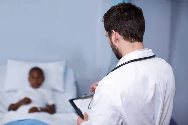 Médico escrevendo na área de transferência no hospital — Fotografia de Stock