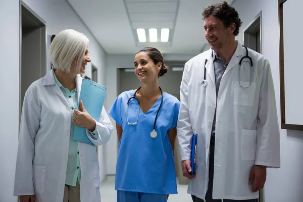 Médicos y cirujanos interactuando en corredor —  Fotos de Stock