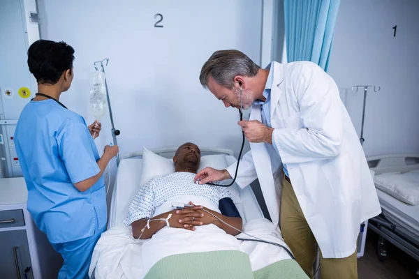 Врач проверяет сердцебиение пациента стетоскопом в палате — стоковое фото