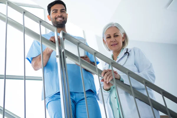 Médicos sonriendo mientras están de pie en la escalera — Foto de Stock