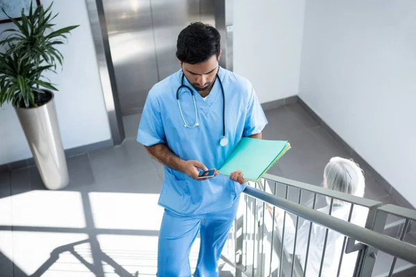 Doctor using phone on staircase — Stock Photo, Image