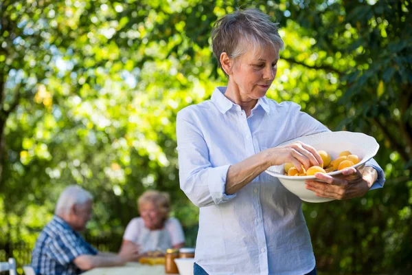 Senior vrouw met een kom met abrikoos — Stockfoto