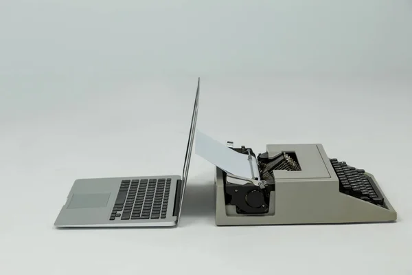 Laptop e macchina da scrivere su sfondo grigio — Foto Stock