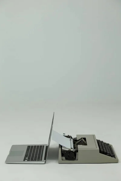 Ноутбук и пишущая машинка на белом фоне — стоковое фото