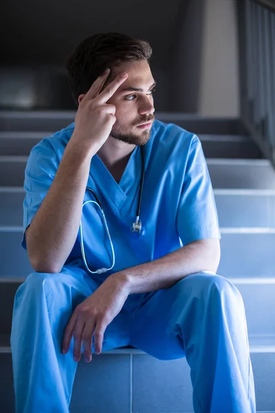 Infirmière masculine réfléchie assise sur un escalier — Photo