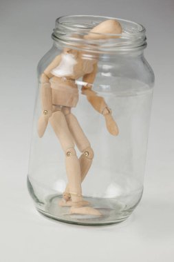Wooden figurine inside a glass jar clipart