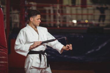 Karate player practicing with nunchaku clipart