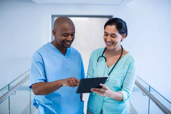 Doctors discussing over digital tablet in corridor — Stock Photo, Image