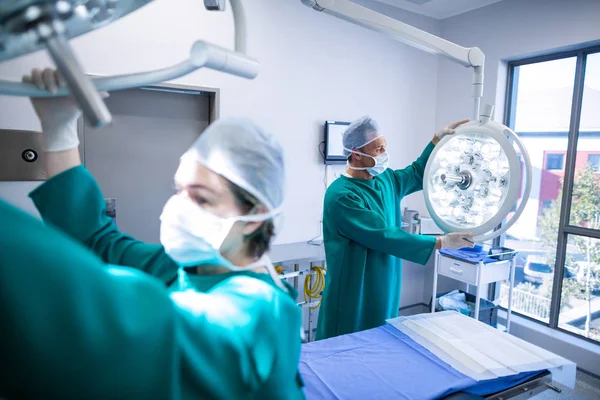 Cirurgiões ajustando a luz cirúrgica — Fotografia de Stock