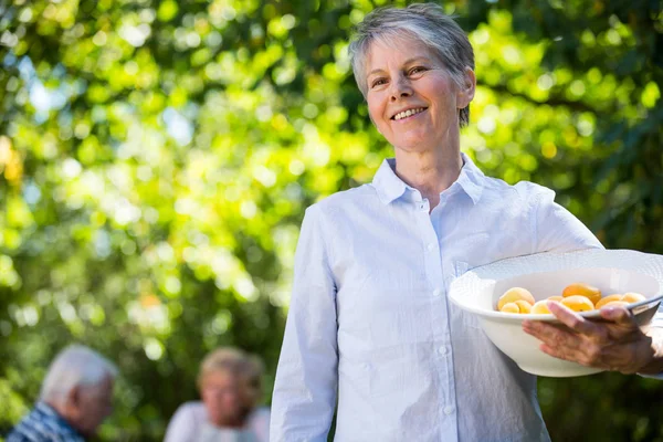 Senior kvinna som håller en skål med aprikos — Stockfoto