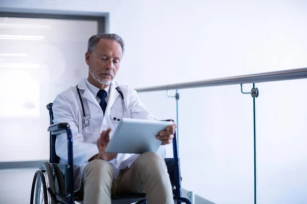Lekarz siedzi na wózku inwalidzkim i za pomocą tabletu — Zdjęcie stockowe