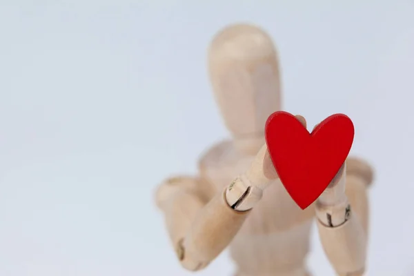 Деревянная фигурка, держащая сердце — стоковое фото