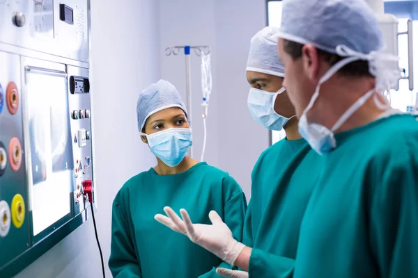 Surgeons discussing a report on surgical monitor — Stock Photo, Image