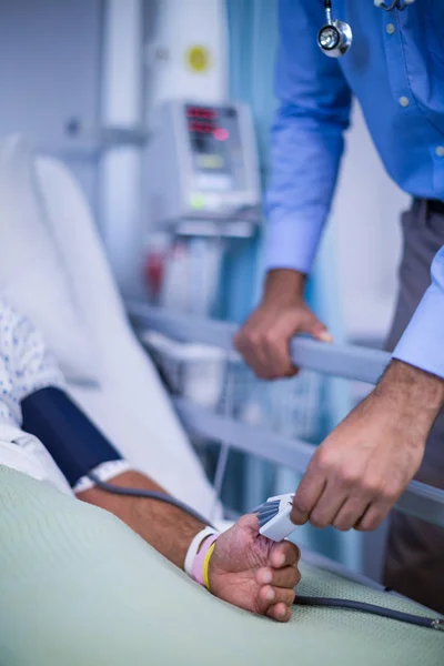 Doctor putting heart rate sensor on patients finger — Stock Photo, Image