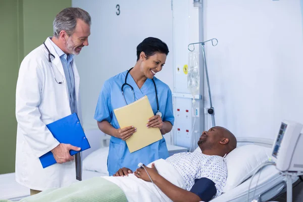 Médico y enfermera interactuando con el paciente durante la visita en sala — Foto de Stock