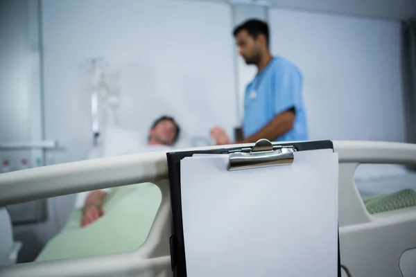 Clipboard hanging on bed in hospital — Stock Photo, Image