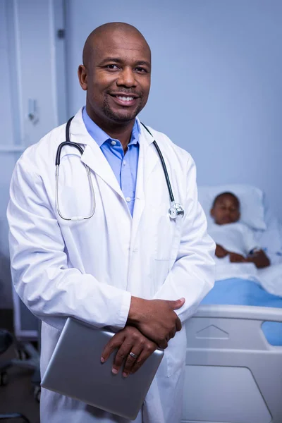 Médecin masculin debout avec comprimé en salle — Photo