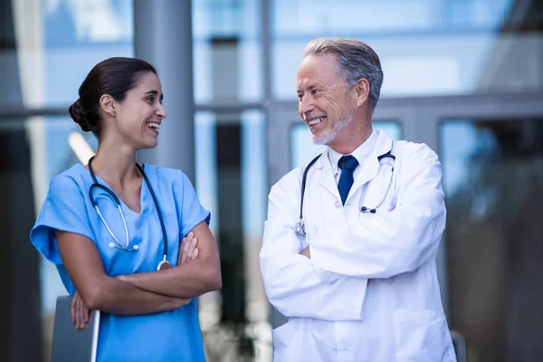 Médico y enfermera de pie con los brazos cruzados — Foto de Stock