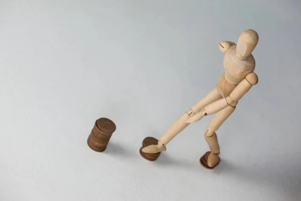 Wooden figurine stepping on coins — Stock Photo, Image