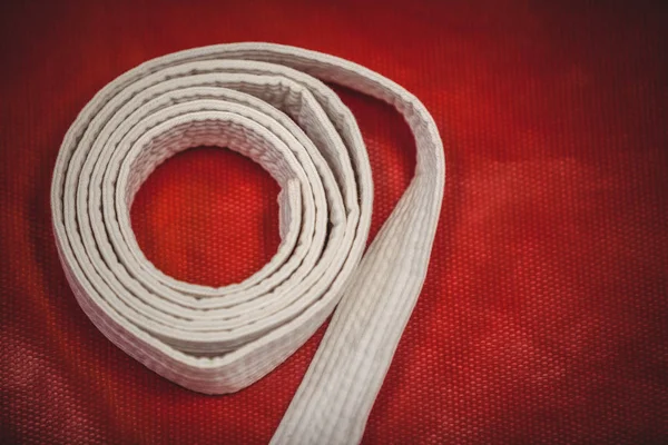 Cinturón blanco Karate sobre fondo rojo — Foto de Stock