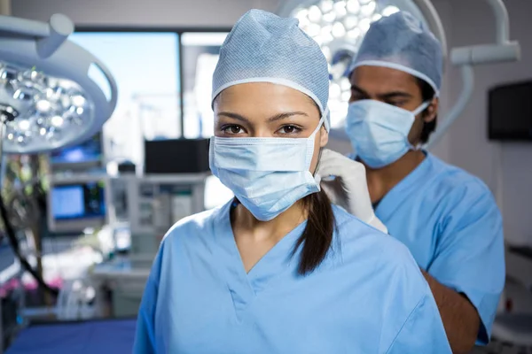 Chirurg hilft beim Binden der Chirurgenmaske an einen Kollegen — Stockfoto