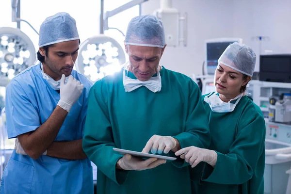 Team av kirurger diskuterar över tablett — Stockfoto