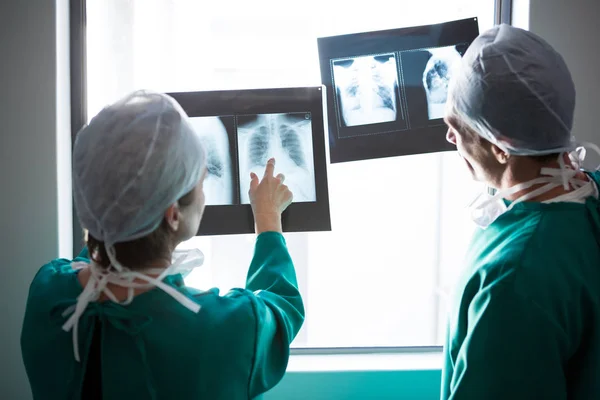 Cirurgiões que examinam um relatório de raios-X no corredor — Fotografia de Stock