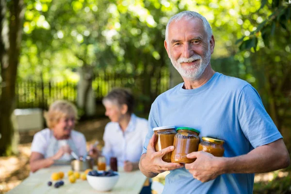 Starszy mężczyzna, trzymając butelkę jam w ogrodzie — Zdjęcie stockowe