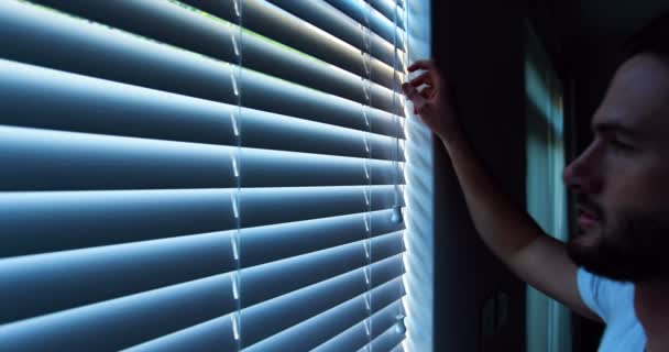 Man looking through window blinds — Stock Video