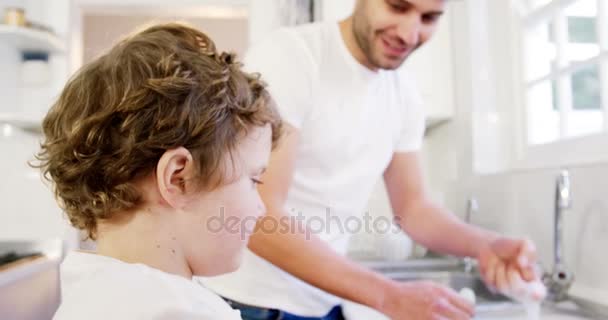 Сын помогает отцу стирать посуду — стоковое видео