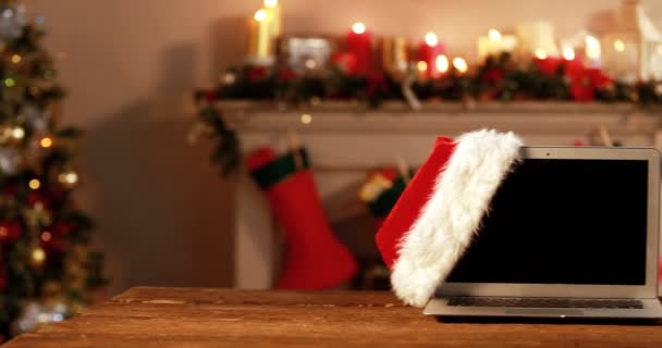 Laptop with santa hat on a wooden table — Stock Video