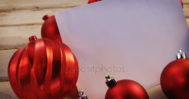 Christmas bauble and paper on plank — Stock Video