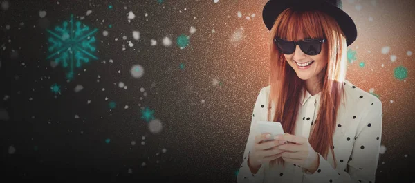 Imagen compuesta de mujer hipster sonriente enviando mensajes de texto con su teléfono inteligente — Foto de Stock