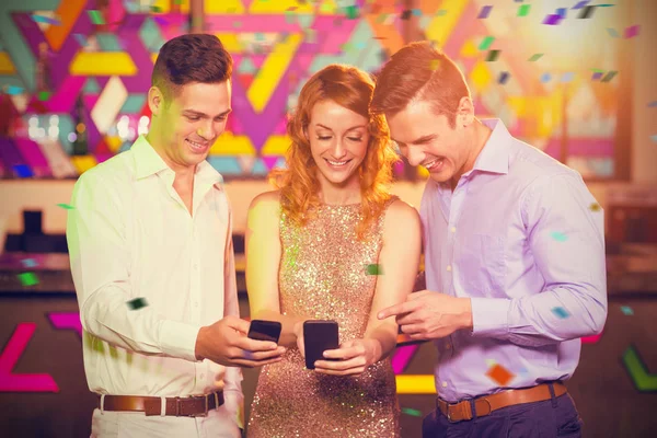 Amigos sonrientes mirando el teléfono móvil — Foto de Stock