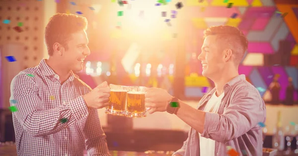 male friends toasting beer mugs at bar