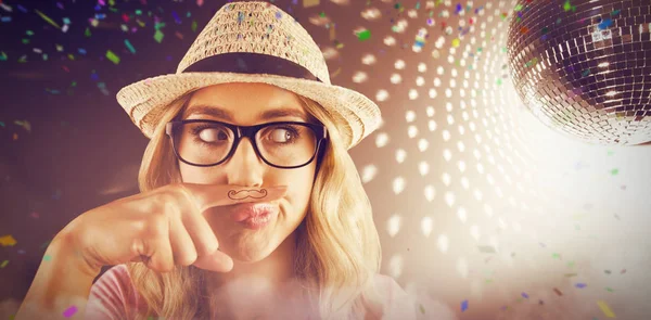 Composite image of a beautiful hipster having a fake mustache — Stock Photo, Image