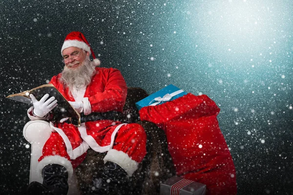Santa reading bible with sack — Stock Photo, Image
