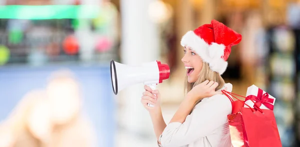 Festive blonde holding megaphone and bags — Stock Photo, Image